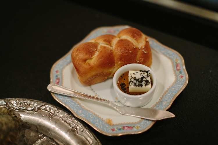 Challah bread loaf with black sesame and served with whipped butter sitting in a puddle of honey at Rose's Luxury